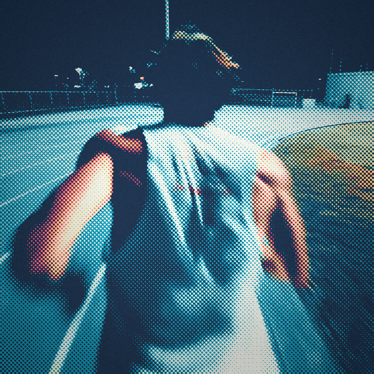 A runner seen from behind, mid-stride on a floodlit track at night